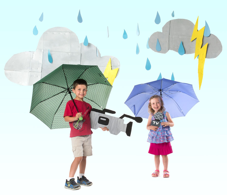 Photo of two children holding umbrellas in cut-outs of rain clouds, rain, and camera