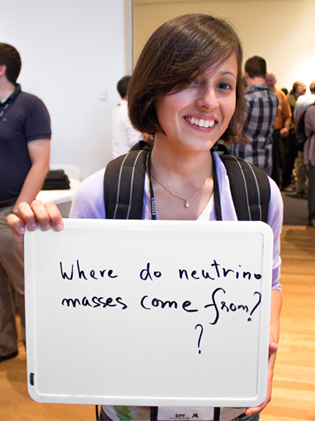 Photo of Kanika Sachdev holding whiteboard that says "Where do neutrons masses come from?"