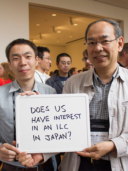 Photo of Akiya Miyamoto and Hiroaki Ono holding whiteboard that says "Does US have interest in an ILC in Japan?"