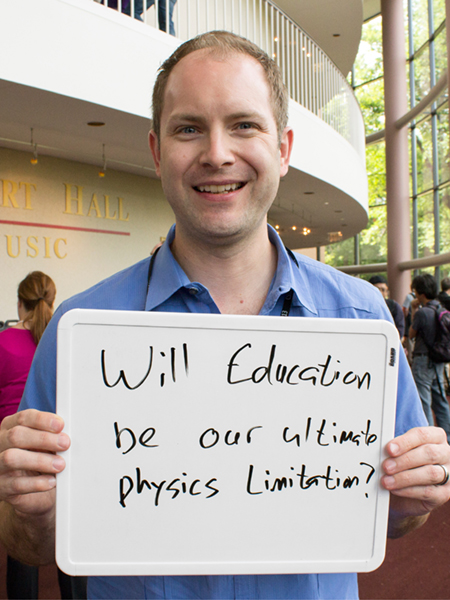 Photo of Wade Fisher holding a whiteboard that says "Will education be our ultimate physics limitation?"