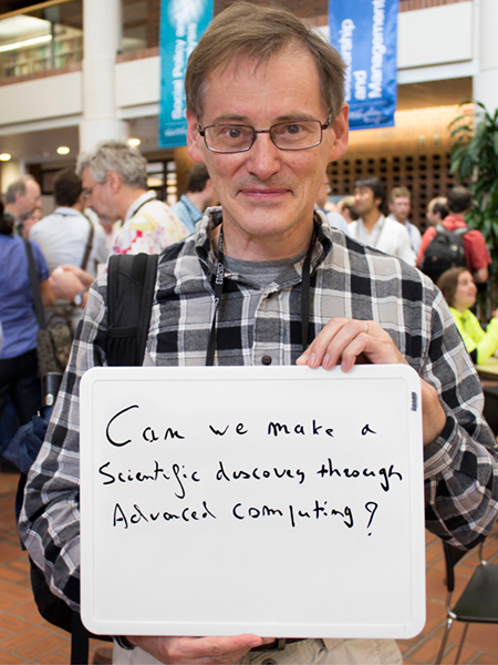 Photo of Paul Lebrun holding a whiteboard that says "Can we make a scientific discovery through advanced computing?"