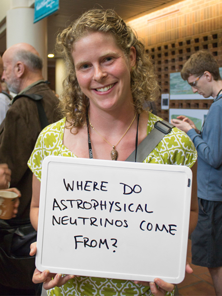 Photo of Abigail Vieregg holding whiteboard that says "Where do astrophysical neutrinos come from?"