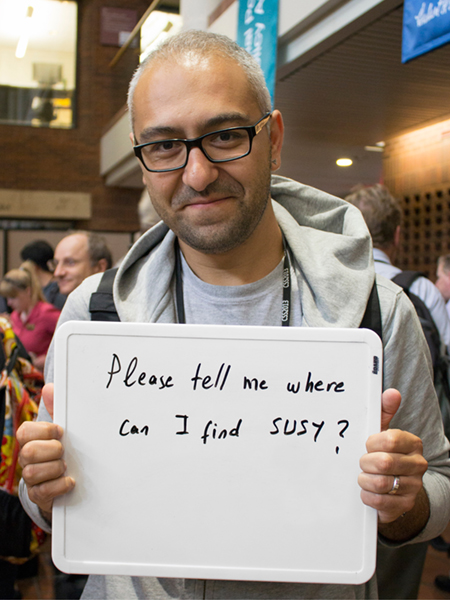 Photo of Altan Cakir holding whiteboard that says "Please tell me where can I find SUSY?"