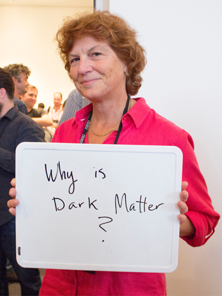 Photo of Prisca Cushman holding whiteboard saying "Why is Dark Matter?"