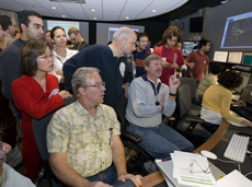 Fermilab Deputy Director Young-Kee Kim and Director Pier Oddone look over the shoulders of Fermilab accelerator scientists Eric Prebys and Elvin Harms at a monitor displaying the beam orbit in the LHC
