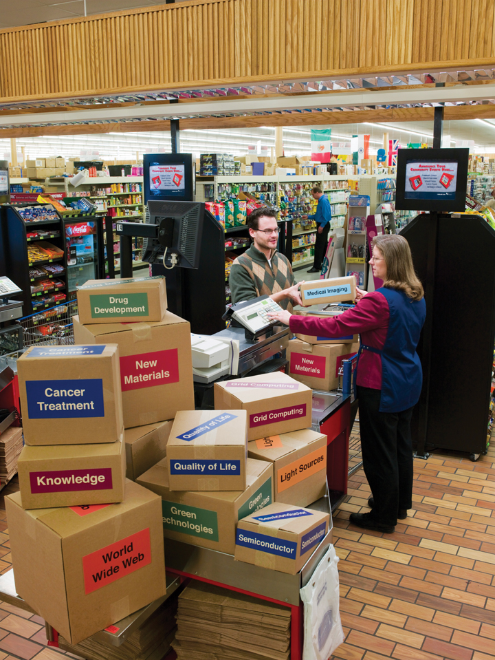 Photo of man at cash register, buying a box from cashier labeled "medical imaging" more boxes that say "cancer treatment" etc.