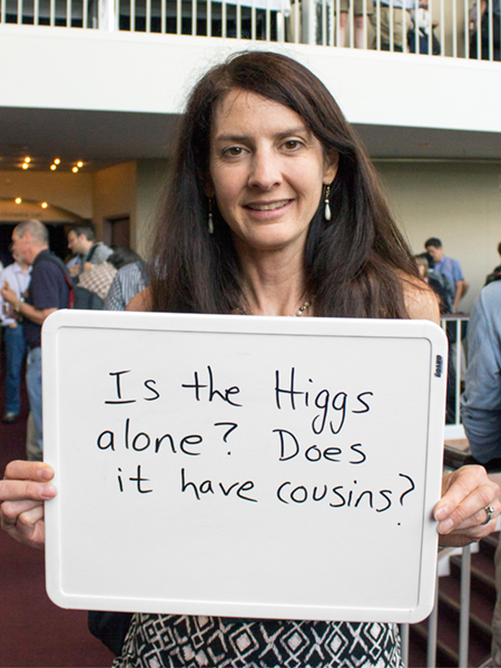 Photo of Robin Erbacher holding whiteboard that says "Is the Higgs alone? Does it have cousins?"