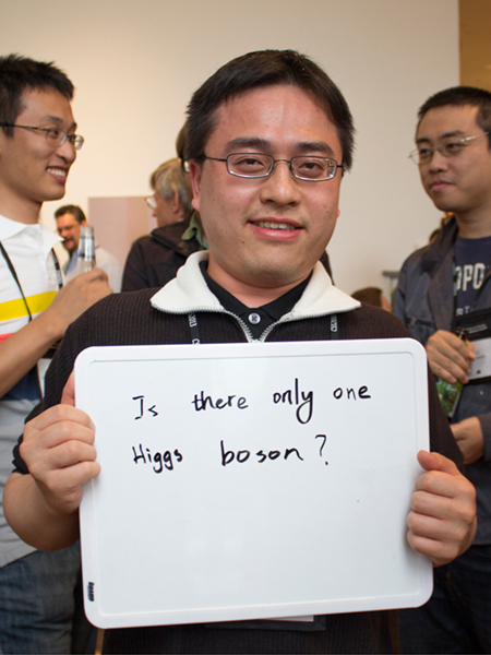 Photo of Chien-Yi Chen holding whiteboard that says "Is there only one Higgs Boson?"