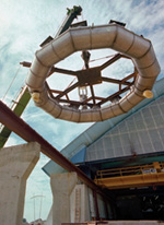 The completed coils are lifted from the building (below) and transported to the magnet. The new coils make the magnet more energy efficient.