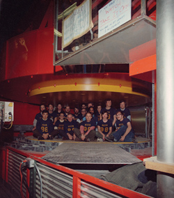 Wearing t-shirts that say "Muon 98," members of the E-98 collaboration at Fermilab gather between the poles of the magnet.