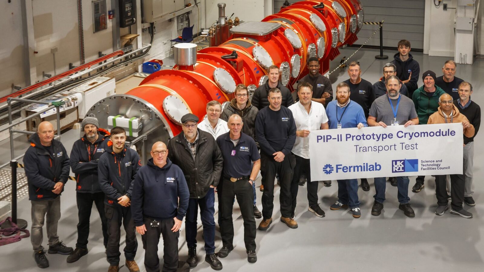 Members of the PIP-II team from Fermilab and STFC UKRI stand in front of the prototype HB650 cryomodule at Daresbury Laboratory