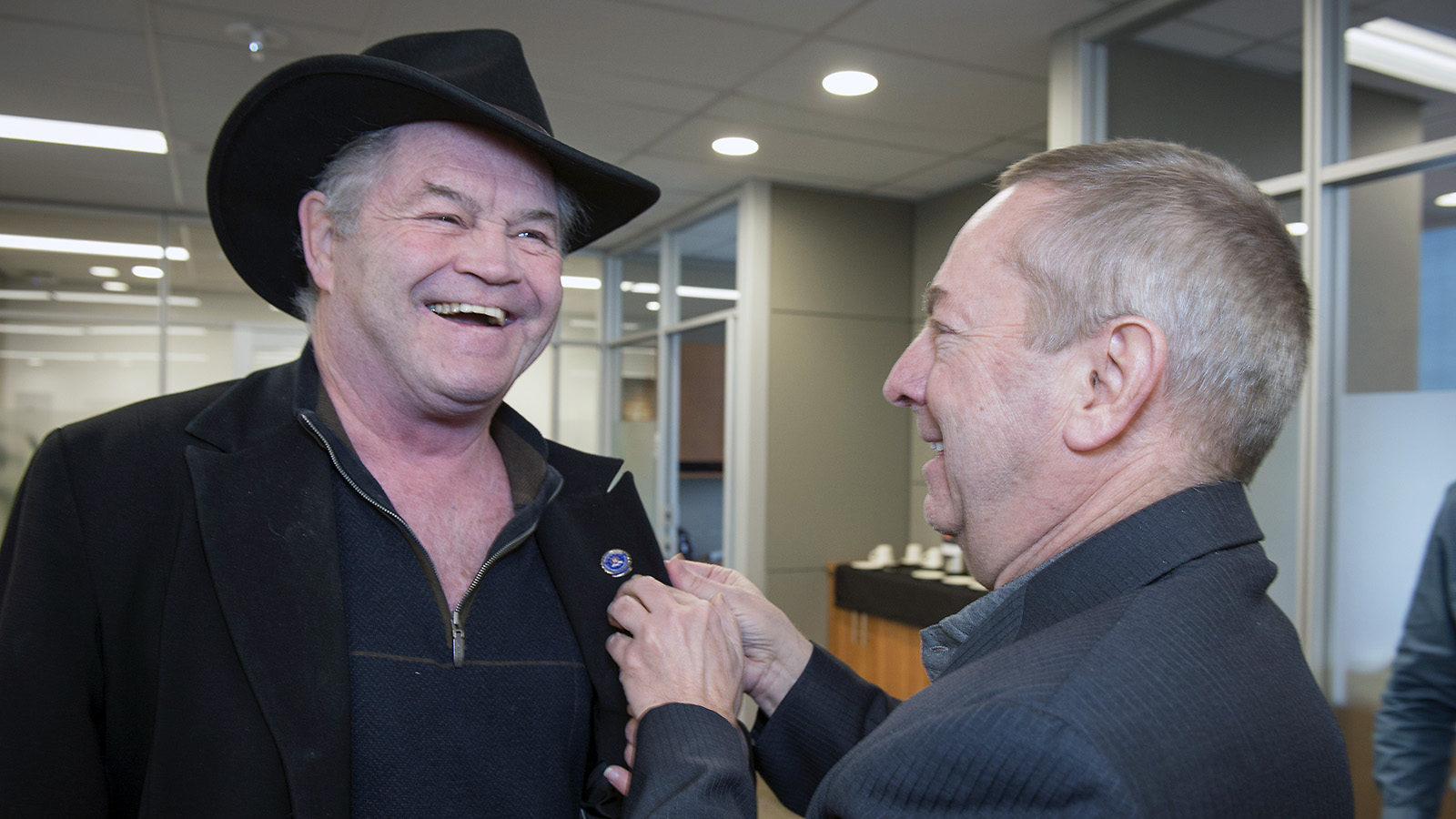 Fermilab Director Nigel Lockyer gives a smiling Micky Dolenz a Fermilab pin