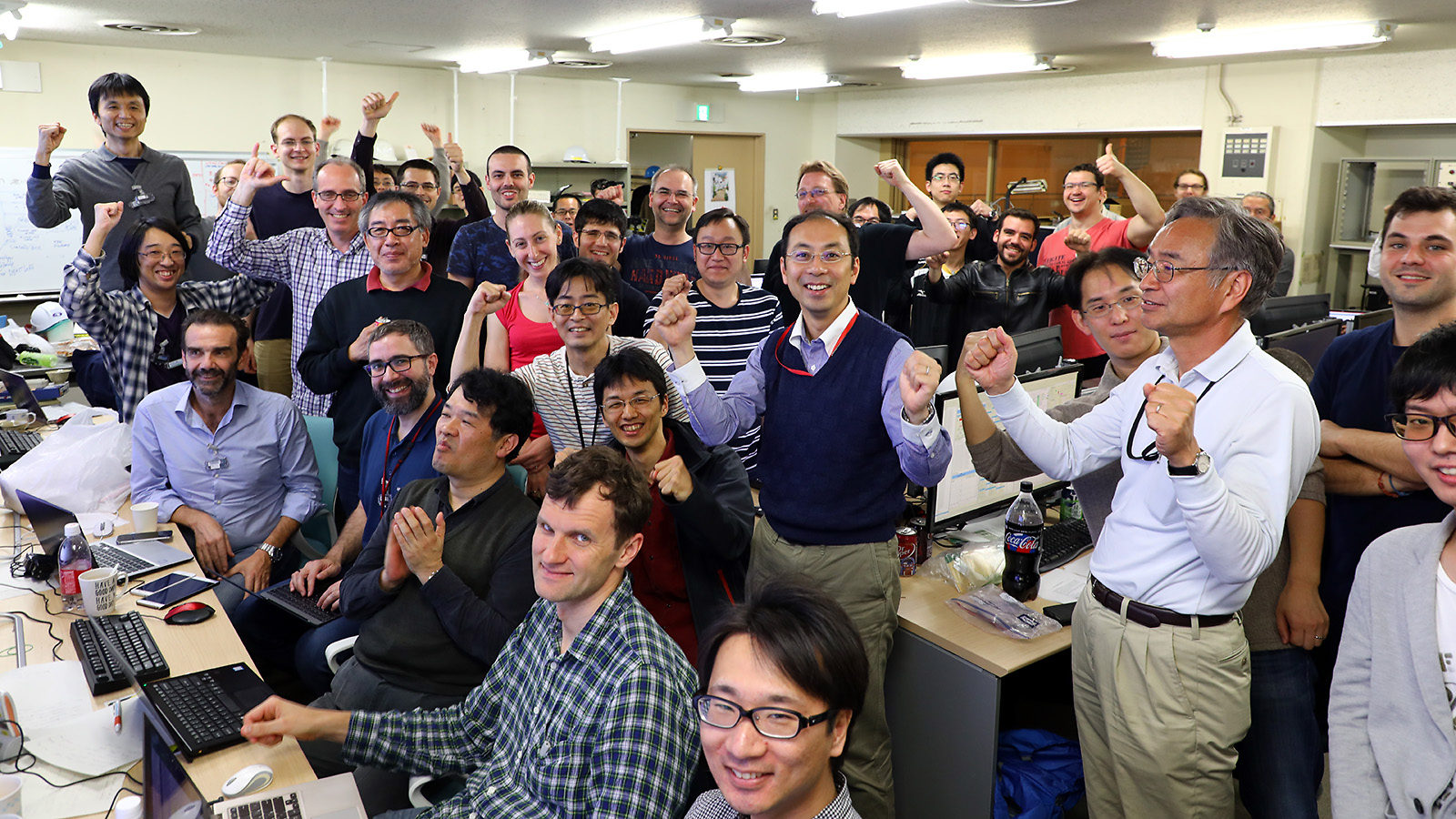 Photo of dozens of researchers celebrating in the control room after first collisions
