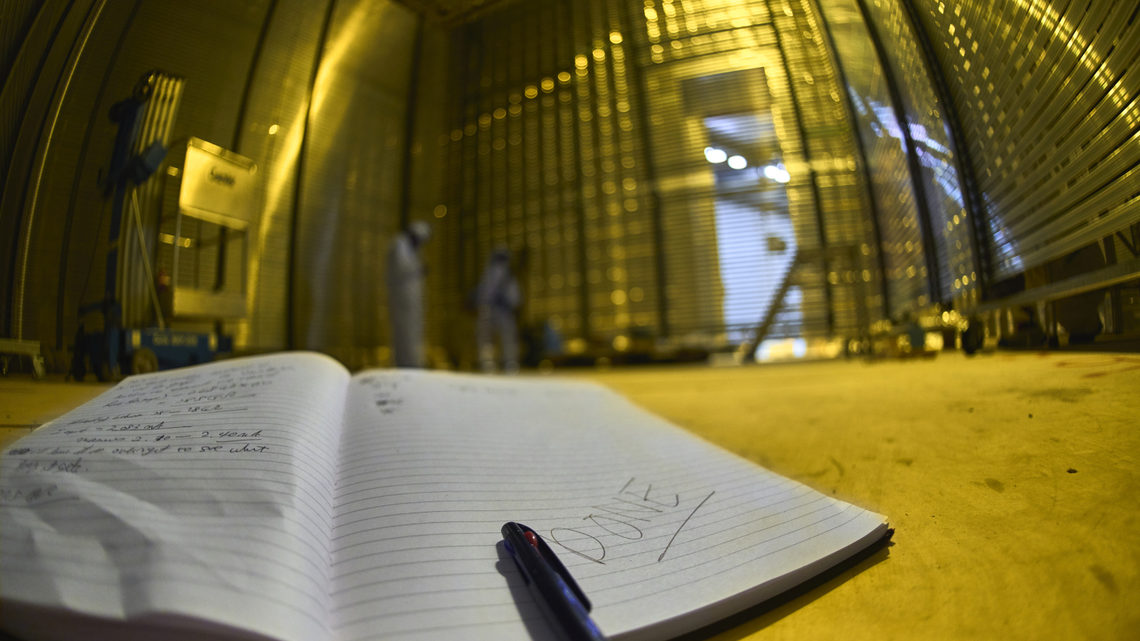 A researchers notebook in the foreground of the detector