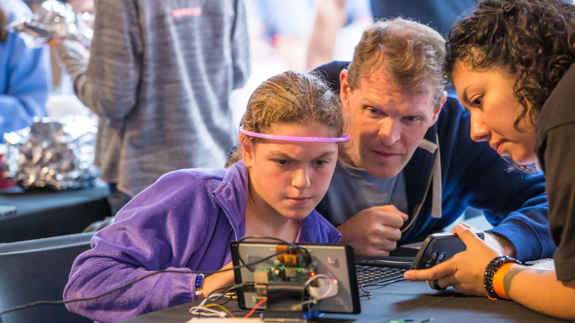 A young girl wearing a glowing headband participates in a hands-on science activity