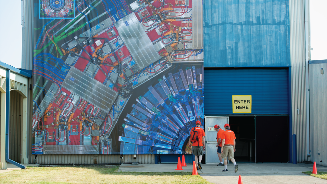 A section of the CMS detector at CERN is displayed on the side of a Fermilab building to provide visitors with a sense of scale.