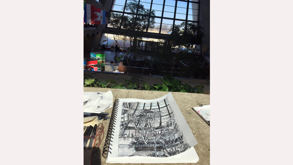 ink drawing of trees in Wilson Hall atrium in a notebook sitting on a ledge in Wilson Hall atrium