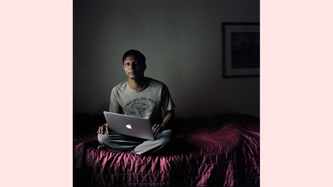 Photo of a young man with a laptop on a bed