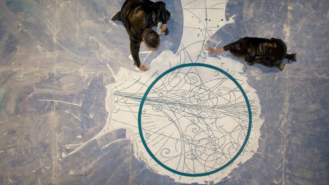 Overhead photograph of artists sweeping around the central circle