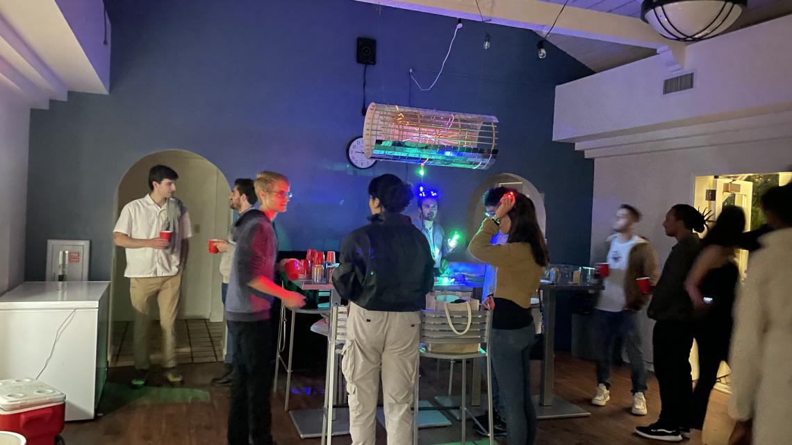 Photograph of several grad students at the class exhibition, with the Disco-tracker hanging from the ceiling