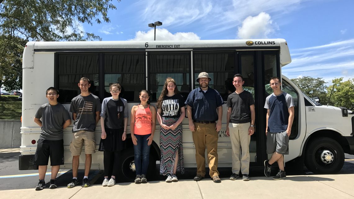 Photo of Glenbrook North High School students standing beside bus