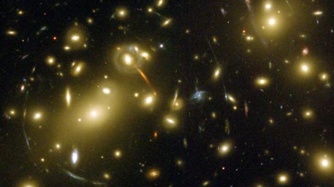 Photo of DEC examining gravitational lensing, or the warping of light from background objects around massive objects foreground