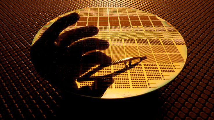 Photo of persons hand on a single silicon wafer
