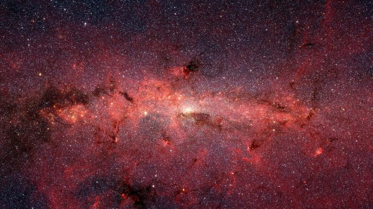 Image of stars and reddish, glowing clouds of dust at the center of the Milky Way Galaxy