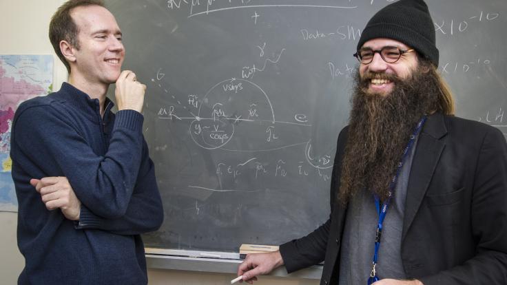 Photograph of scientist James Wells with artist Julius von Bismarck in front of a chalkboard full of equations