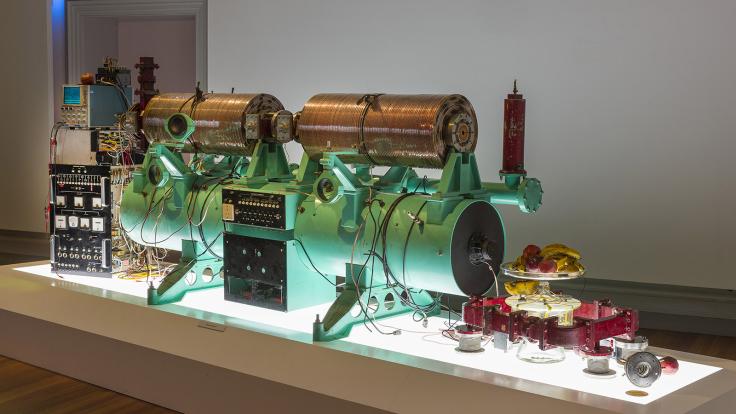 Green piece of an accelerator machinery and a plate of fruit on a lit table