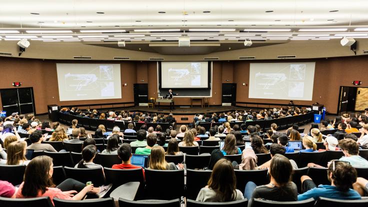 A lecture hall full of students watching a presentation