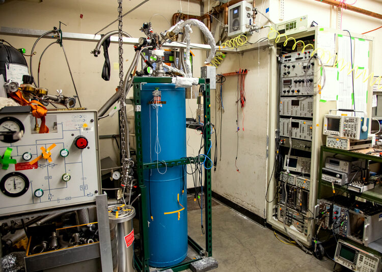 Photo of a tall blue tank in a room full of experimental equipment